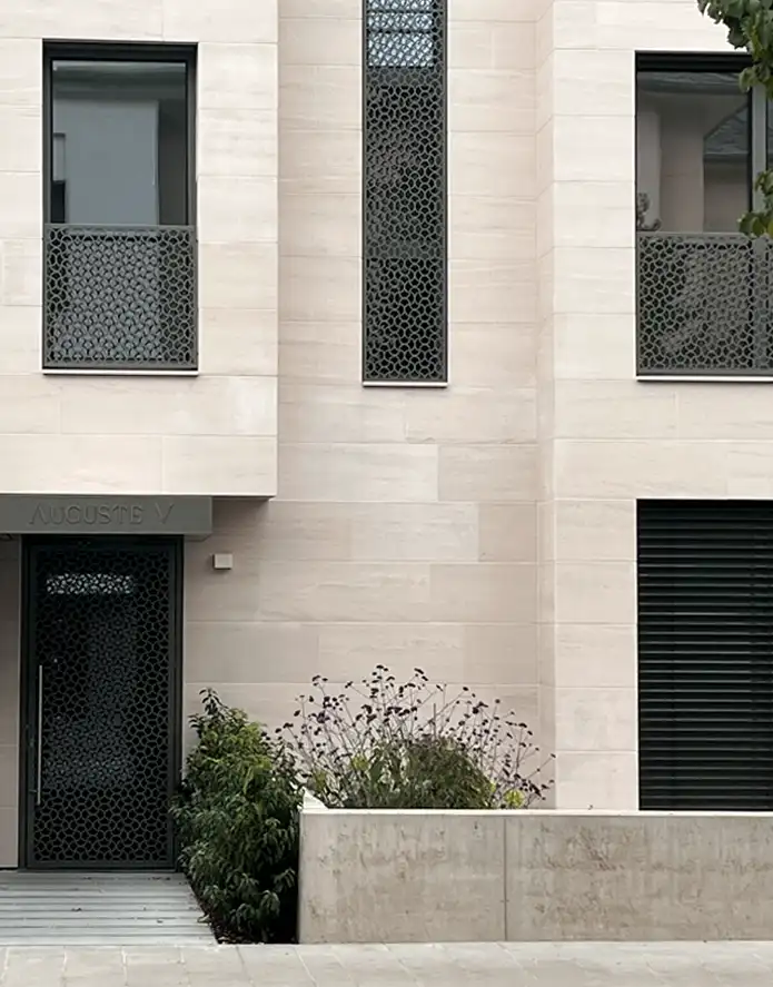 Façade en pierre claire de la résidence Auguste V à Luxembourg, avec le logo gravé au-dessus de la porte d’entrée.